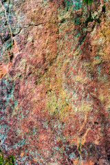 Pattern of granite stone wall covered with moss and lichen, as a background, closeup, details.