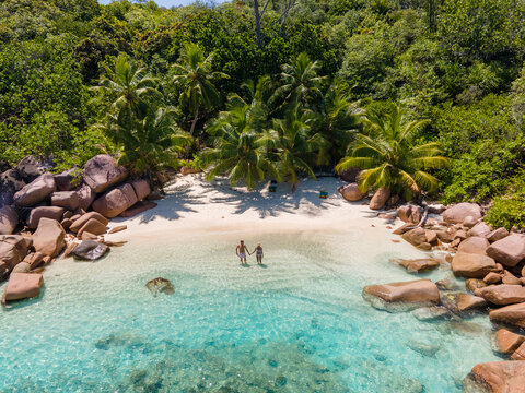 Praslin Seychelles tropical island with withe beaches and palm trees, couple of men and women mid age on vacation at Seychelles visiting the tropical beach Anse Lazio Praslin Seychelles. drone view 