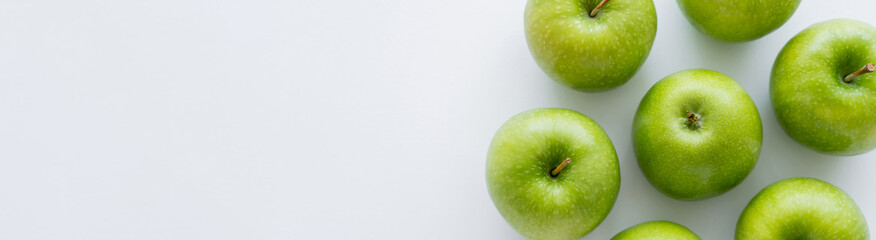 top view of whole green apples on white with copy space, banner. - obrazy, fototapety, plakaty