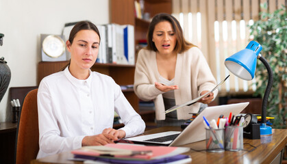 Outraged business woman expressing dissatisfaction with work of confused secretary in office