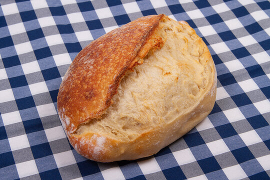 Whole loaf of freshly baked Scoring bread on checkered blue white background
