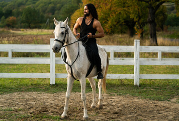 Handsome muscular man riding horse. Hunky cowboy. Young muscular guy in t-shirt on horseback.