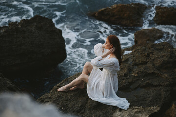 beautiful woman in white dress wet hair stone beach cloudy weather