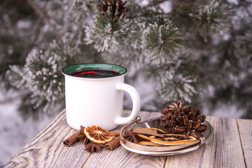 Close-up of a ceramic white mug with mulled wine and spices on a wooden table in winter.