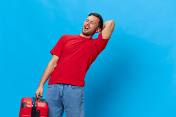 Overjoyed excited happy tanned handsome man in red t-shirt preparing for holiday hold big suitcase posing isolated on blue studio background. Copy space Banner Mockup. Trip journeys concept
