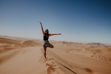 Fototapeta na wymiar Junge Frau macht Yoga Pose im Sand auf einer Düne