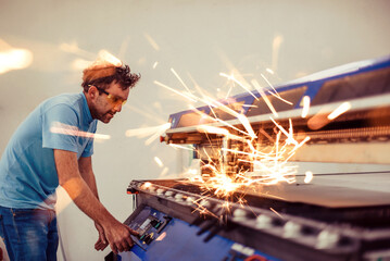 Within heavy industry. A man works in a modern factory on a CNC machine. Selective focus