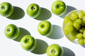 top view of ripe apples near tasty grapes in bowl on white.