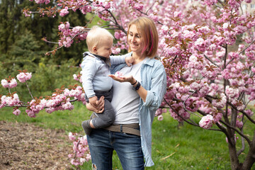 mother with adorable little son in park with Sakura Cherry blossom tree. Happy mother and child.