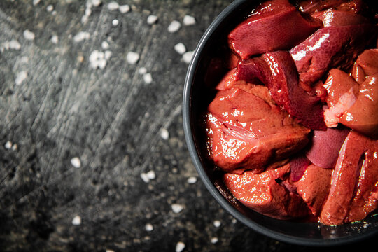 Sliced raw liver in a bowl. On a black background. High quality photo