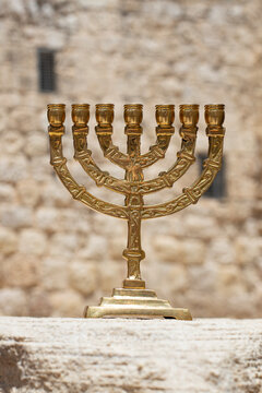 A gold menorah with a background of the walls of Jerusalem