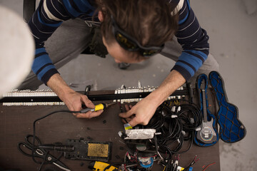 Industrial worker man soldering cables of manufacturing equipment in a factory. Selective focus