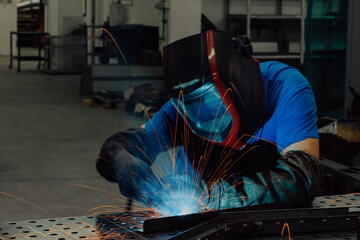 Fototapeta na wymiar Professional Heavy Industry Welder Working Inside factory, Wears Helmet and Starts Welding. Selective Focus