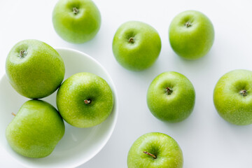 top view of bowl with organic apples on white.