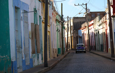 Fototapeta na wymiar Street with its colorful houses and one old car in the middle, Camaguey, Cuba