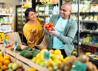 Man and woman picking ripe tomatoes together at grocery store