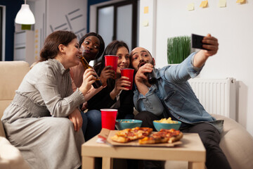 Business people taking pictures on smartphone at office party with drinks and snacks after work hours. Colleagues using mobile phone to take selfies and make memories at fun celebration.