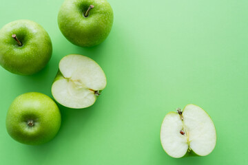flat lay of whole and cut juicy apples on green.