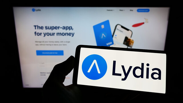 Stuttgart, Germany - 04-03-2022: Person holding smartphone with logo of French company Lydia Solutions SAS on screen in front of website. Focus on phone display.