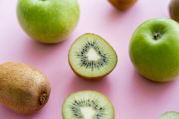 Fototapeta premium close up view of apples and sweet kiwi on pink.