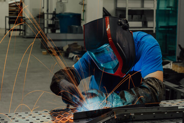 Professional Heavy Industry Welder Working Inside factory, Wears Helmet and Starts Welding. Selective Focus