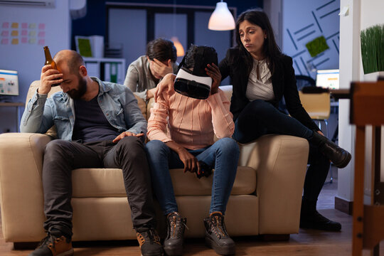 Disappointed woman with vr headset losing at video games on tv console, using virtual reality glasses and controller to play for entertainment. Office colleagues meeting for drinks after hours.