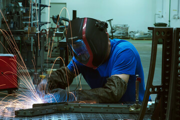Professional Heavy Industry Welder Working Inside factory, Wears Helmet and Starts Welding. Selective Focus
