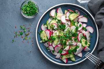 Fresh vegetable salad with radishes, herbs and flax seeds on a dark background. Top view, copy space.