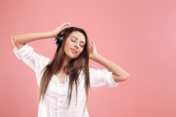 Fototapeta na wymiar Young woman on pink background listening to music with wireless headphones