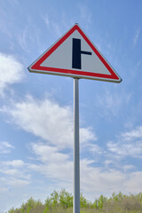 Road sign warning turn from main road blue sky background.