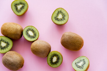 top view of cut green kiwi on pink.
