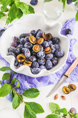 White handmade bowl filled with ripe plums