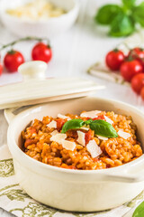 Homemade tomato risotto with fresh basil on a white wooden table
