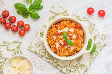 Homemade tomato risotto with fresh basil and parmesan cheese on a white wooden table