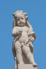 Fototapeta na wymiar Old statue of a small child in the historical downtown of Dresden, Germany, at blue sky background.