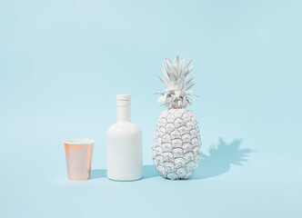 Summer background with white fresh pineapple, drinking bottle and golden paper cup. Minimal summer drink concept.
