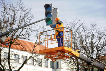 Man in uniform on aerial platform fix and repair broken traffic signal. Traffic lights repair...