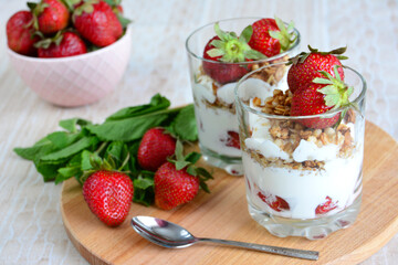 healthy dessert with oatmeal, yoghurt and fresh strawberries on beige background