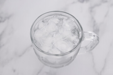 drinking enough water or sobriety concept, pint glass with tap water and ice cubes over marble background