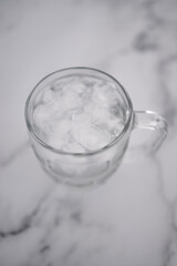 drinking enough water or sobriety concept, pint glass with tap water and ice cubes over marble background