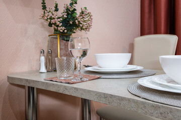 served table in the living room or kitchen with cups, plates, glasses and flowers