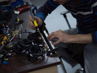 Industrial worker man soldering cables of manufacturing equipment in a factory. Selective focus