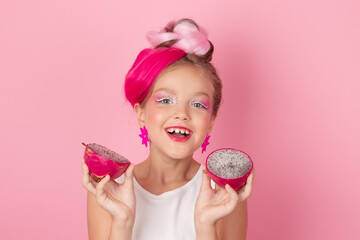 Close-up portrait of pretty girl with pink hairstyle with dragon fruit on pink background. Studio...