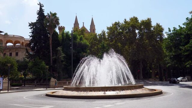Still shot of the Fountain at Placa De La Reina (Reina Square) with the cathedral spires in the background - Palma de Mallorca, Spain