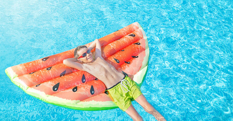Happy nine years old caucasian child (boy) in red sunglasses having fun on  air  (inflatable) mattress in form of a watermelon, swimming pool. Kid water toys, summer holiday, resort. Beach vacation.