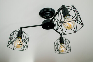 Geometric lamp hangs on a white ceiling. Modern, minimalist lamp that successfully complements the interior in loft style