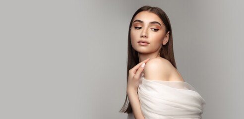 Obraz premium Portrait of tender young woman covered with white veil isolated over grey background. Flyer