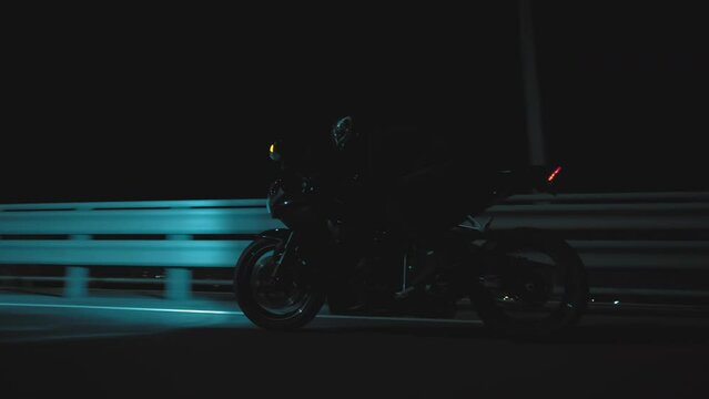 A man rides a sports motorcycle through the city at night