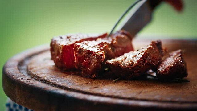 BBQ in the garden. Person cuts filet mignon cooked on the charcoal grill