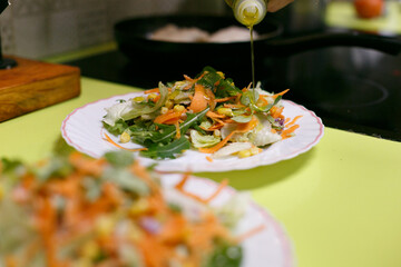 Aderezando ensalada variada con aceite de oliva virgen, plato vegano
